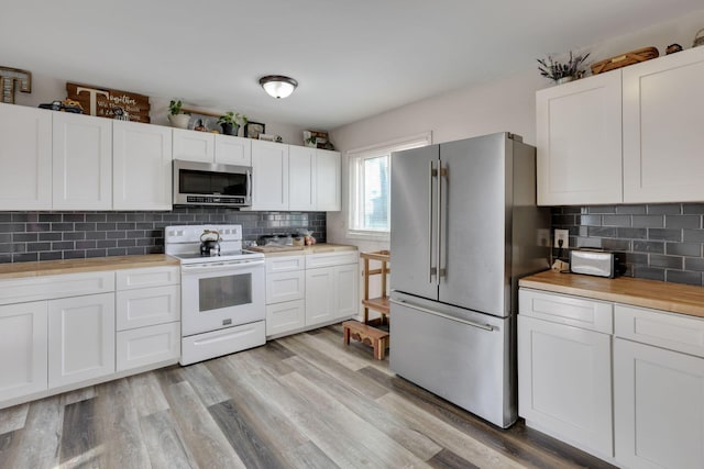 kitchen featuring light wood-type flooring, backsplash, appliances with stainless steel finishes, and white cabinetry