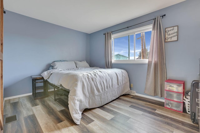 bedroom with visible vents, baseboards, and wood finished floors