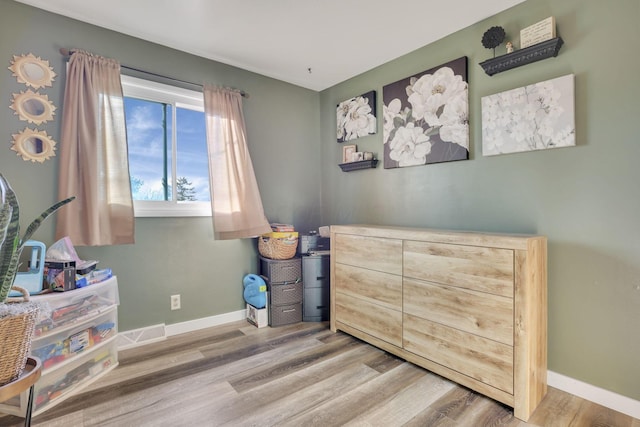 bedroom with visible vents, baseboards, and wood finished floors