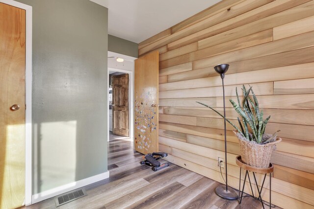 interior space featuring visible vents, wooden walls, and wood finished floors