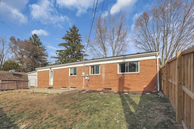 rear view of property with brick siding, a lawn, a patio, and a fenced backyard