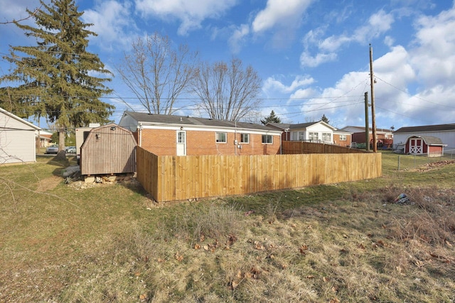 view of yard with an outdoor structure, a storage unit, fence, and a residential view