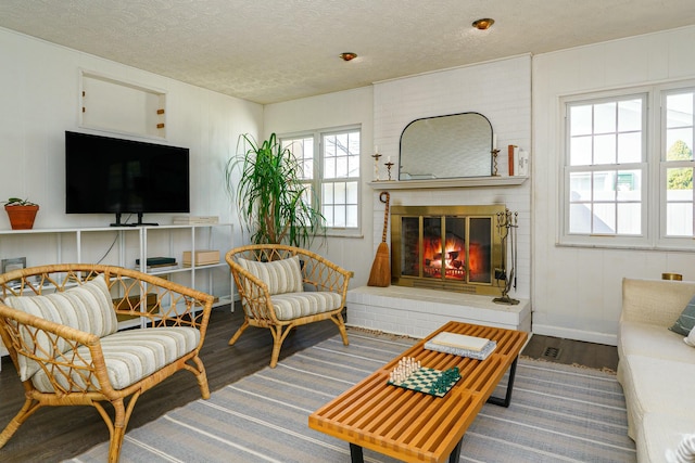 living room with wood finished floors, a fireplace, and a textured ceiling