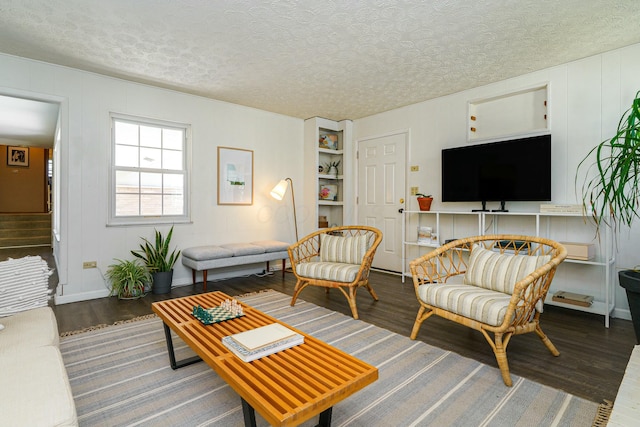 living area featuring a textured ceiling, wood finished floors, and stairs