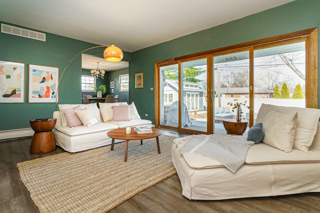 living area with wood finished floors, baseboards, visible vents, a baseboard radiator, and a chandelier