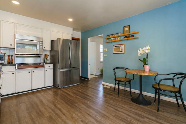 kitchen featuring dark wood-style flooring, decorative backsplash, white cabinets, appliances with stainless steel finishes, and dark countertops