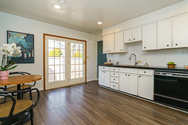 kitchen with a sink, backsplash, dark countertops, dark wood finished floors, and dishwasher