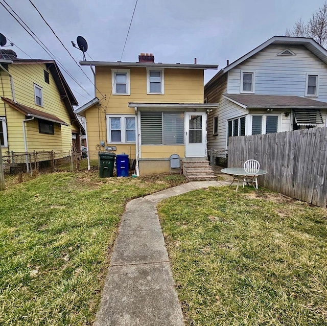 rear view of property with a yard, fence, and entry steps