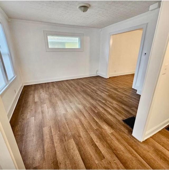 spare room featuring visible vents, a textured ceiling, baseboards, and wood finished floors