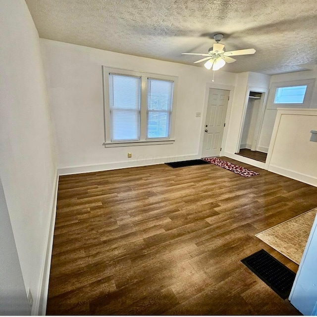 interior space with visible vents, a textured ceiling, baseboards, and wood finished floors