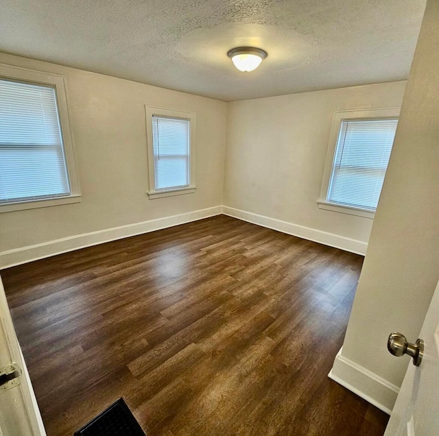 unfurnished room featuring baseboards, a textured ceiling, and dark wood-style floors