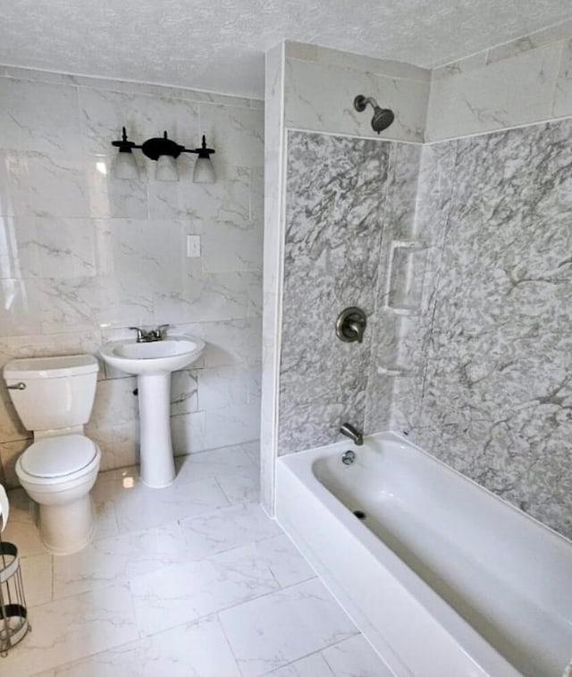 bathroom with shower / bath combination, toilet, marble finish floor, and a textured ceiling