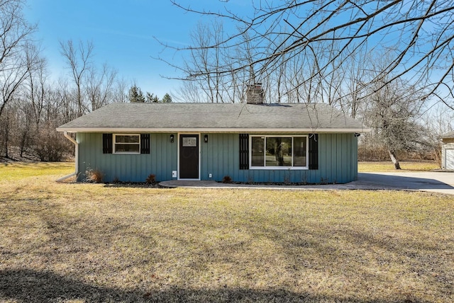 ranch-style home with board and batten siding, a chimney, and a front lawn