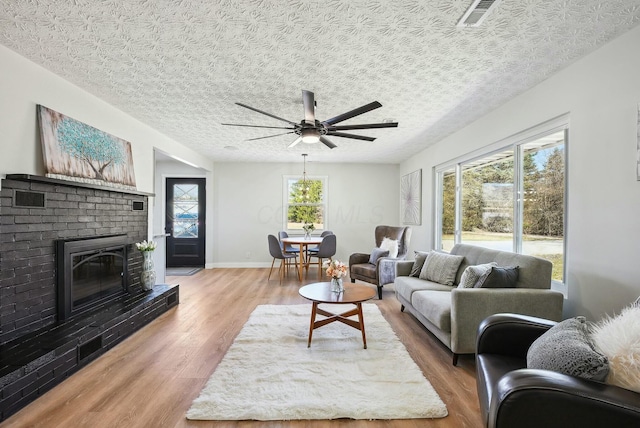 living area featuring visible vents, a healthy amount of sunlight, and wood finished floors