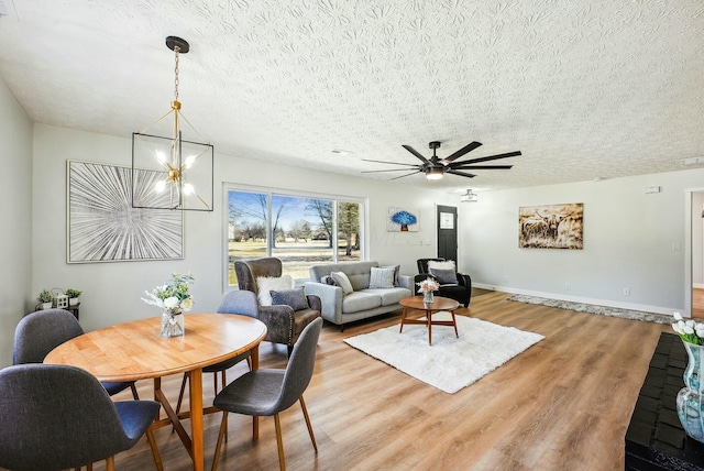 living room with baseboards, a textured ceiling, and light wood-style flooring