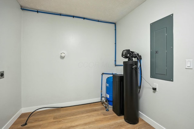 washroom featuring electric panel, wood finished floors, and baseboards