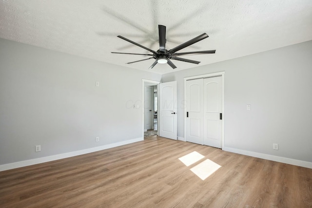 unfurnished bedroom with a ceiling fan, a textured ceiling, a closet, light wood finished floors, and baseboards