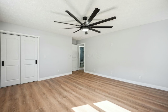 unfurnished bedroom with a closet, a textured ceiling, light wood-type flooring, and baseboards