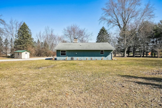 back of property with a storage shed, an outbuilding, a yard, and a chimney