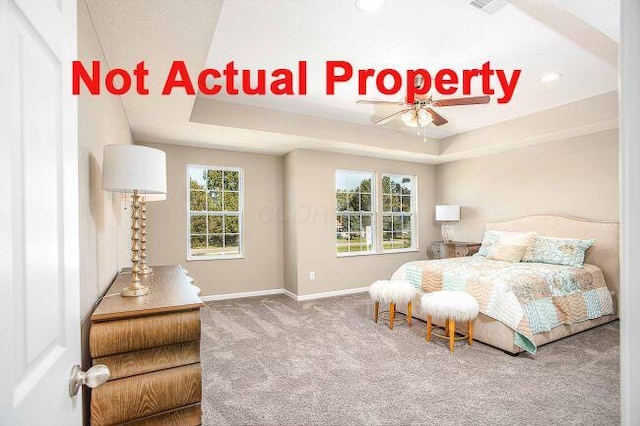 carpeted bedroom featuring a raised ceiling and baseboards