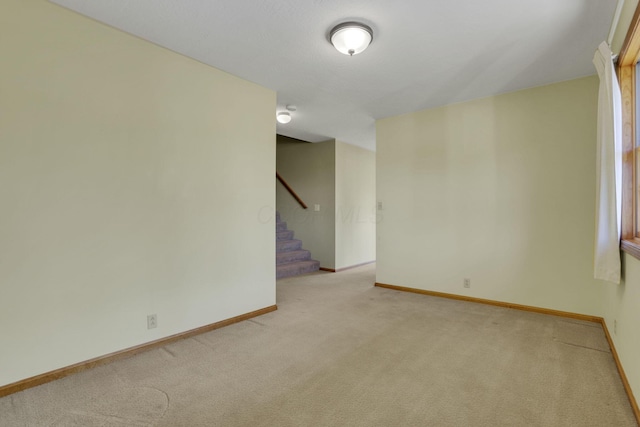 empty room with light colored carpet, stairs, and baseboards