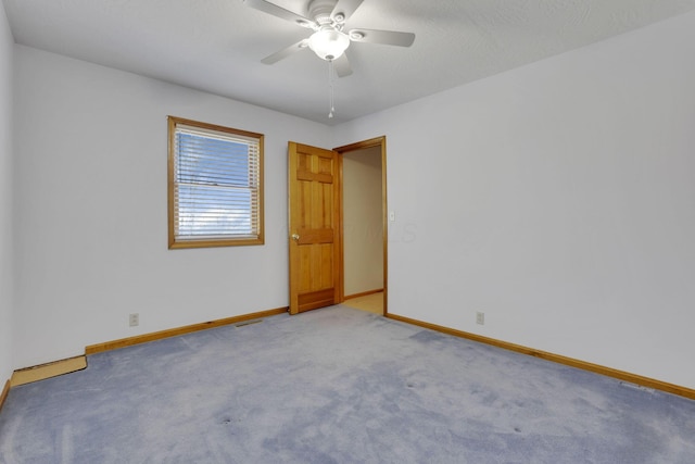 spare room featuring a ceiling fan, visible vents, light colored carpet, and baseboards