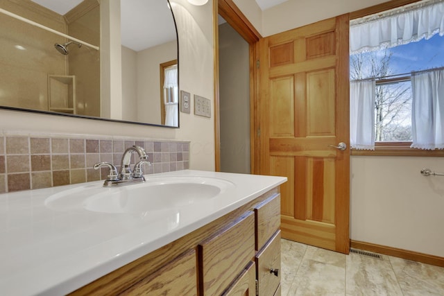 bathroom with vanity, visible vents, baseboards, decorative backsplash, and walk in shower