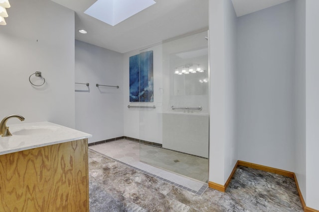 bathroom with baseboards, a skylight, vanity, and a walk in shower