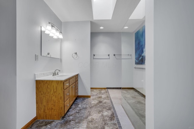 bathroom with a skylight, recessed lighting, vanity, and baseboards