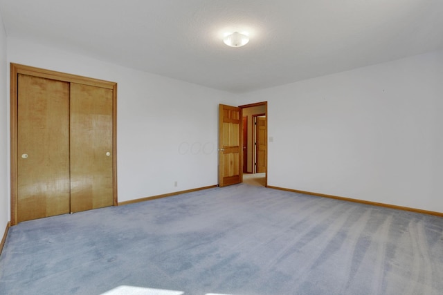 unfurnished bedroom featuring a closet, baseboards, and carpet flooring