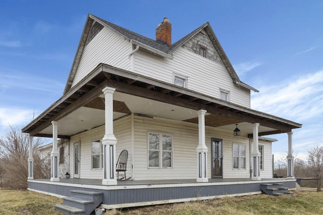 view of front facade with covered porch and a chimney