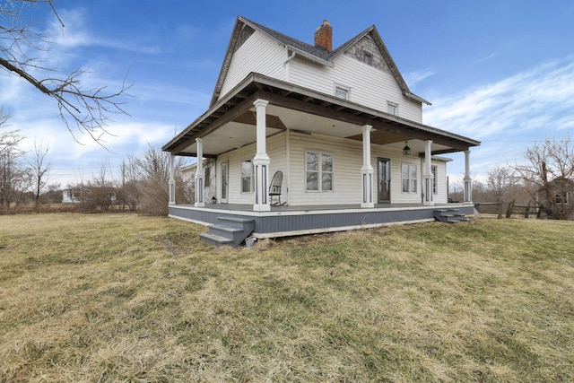 rear view of property featuring a lawn, covered porch, and a chimney