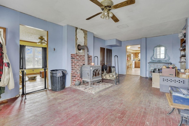 sitting room featuring hardwood / wood-style flooring, a wood stove, and a ceiling fan