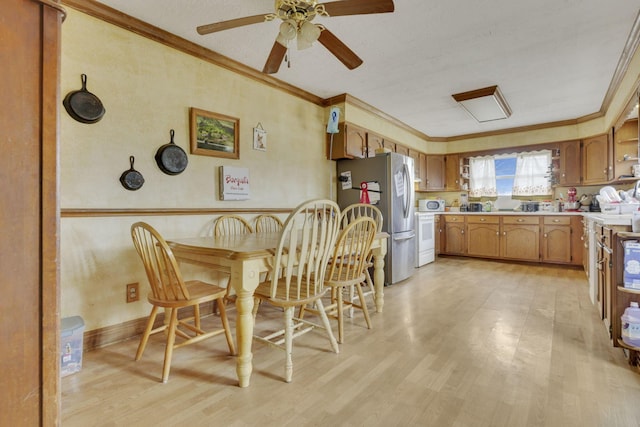 kitchen featuring crown molding, light countertops, light wood-style floors, and freestanding refrigerator