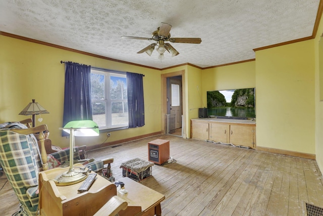 living area with visible vents, ornamental molding, a textured ceiling, light wood finished floors, and baseboards