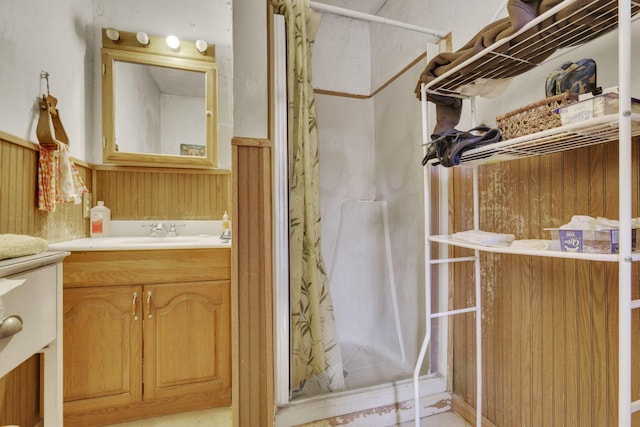 full bath with a wainscoted wall, wooden walls, vanity, and a shower stall