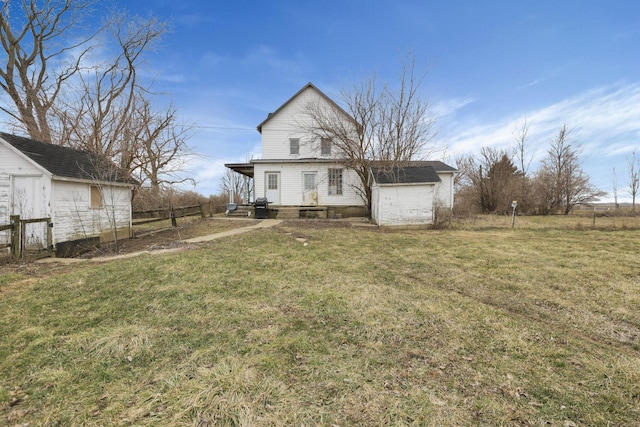 back of property featuring an outbuilding, a yard, and fence