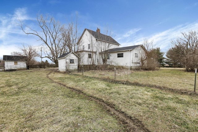 view of side of home featuring a lawn, fence, and a chimney