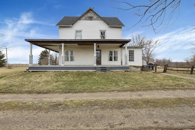 back of house featuring a lawn, covered porch, a shingled roof, and fence