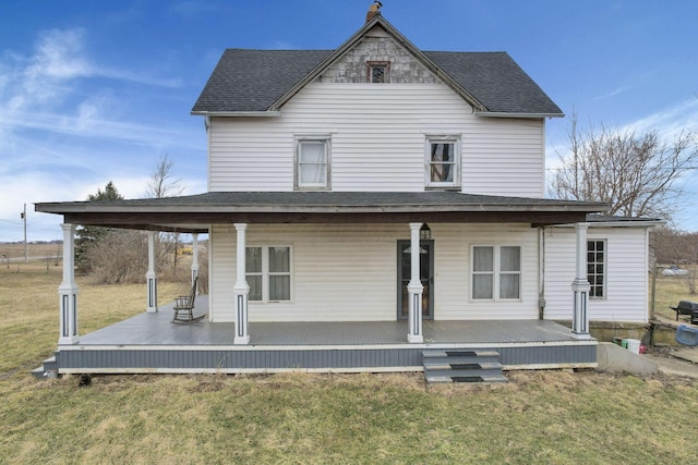 back of house featuring a yard, covered porch, and a shingled roof