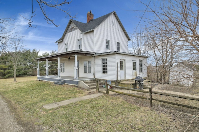 view of front of property featuring covered porch, a chimney, a front yard, and a shingled roof