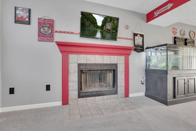 unfurnished living room with a tiled fireplace, a textured ceiling, baseboards, and carpet floors