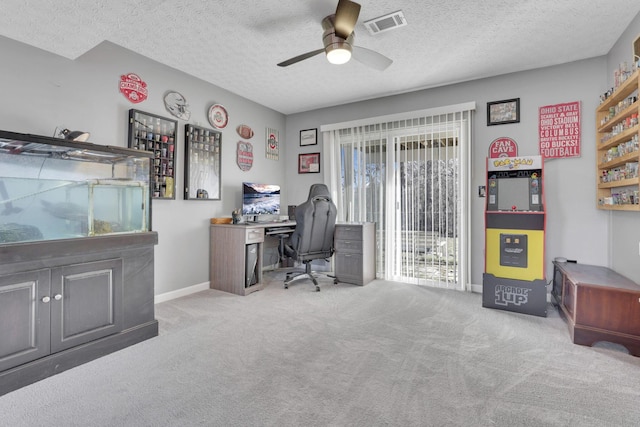 carpeted office space featuring ceiling fan, baseboards, visible vents, and a textured ceiling