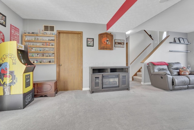 interior space featuring visible vents, a textured ceiling, a glass covered fireplace, and carpet floors