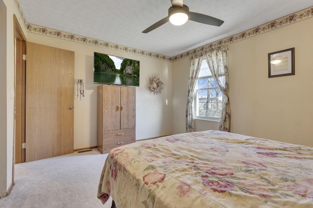 carpeted bedroom featuring baseboards, a ceiling fan, visible vents, and a textured ceiling