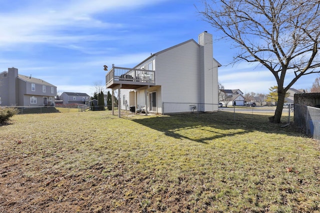 rear view of house featuring a yard, a deck, a fenced backyard, and a chimney