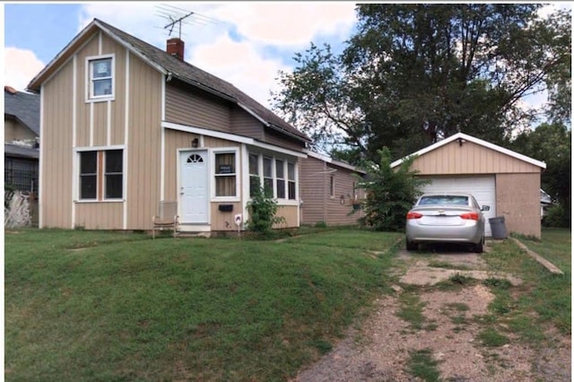 view of front of home featuring a chimney, a detached garage, and a front lawn