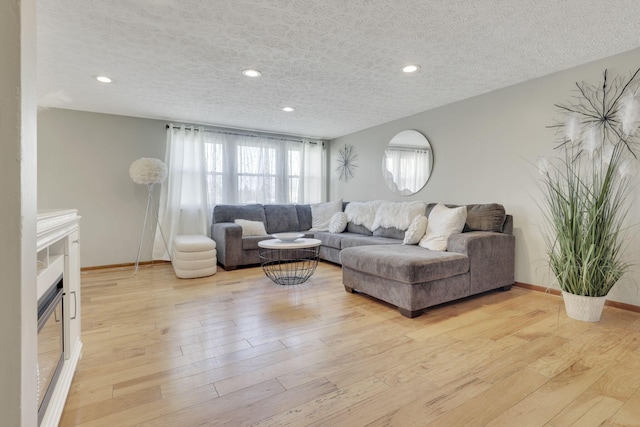 living area with baseboards, a fireplace, recessed lighting, light wood-style floors, and a textured ceiling