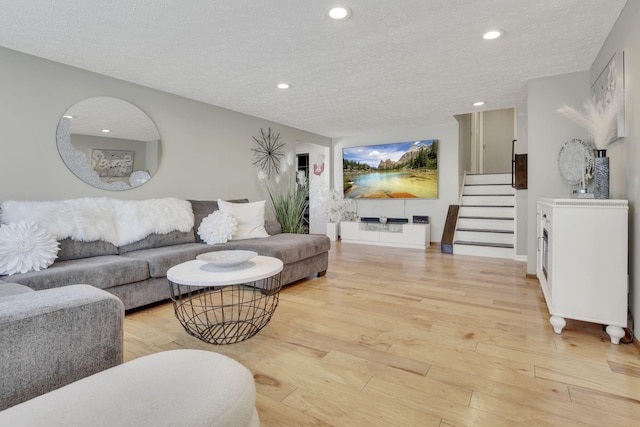 living room with stairs, light wood-style flooring, recessed lighting, and a textured ceiling