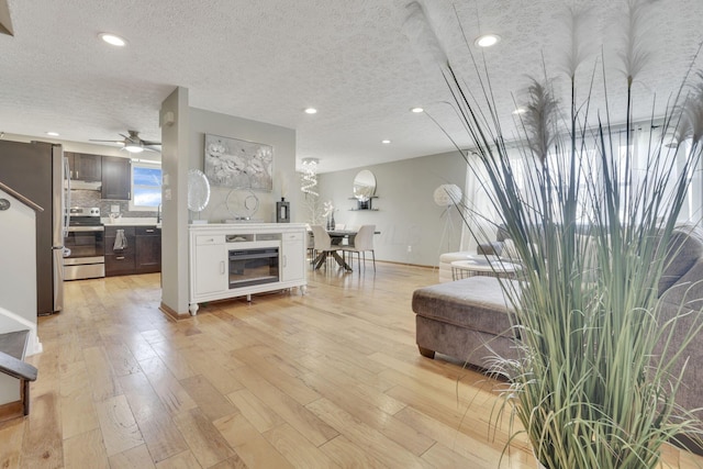 living room with recessed lighting, a textured ceiling, a ceiling fan, and light wood finished floors